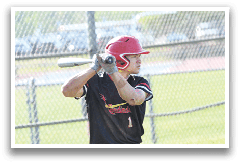 A baseball player in a black shirt and red helmet is holding a bat. Description generated by AI