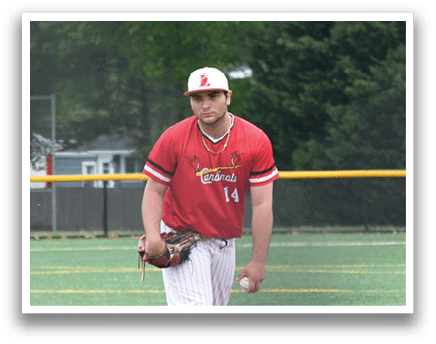 A baseball player in a red shirt and white pants is standing on a pitcher's mound. Description generated by AI