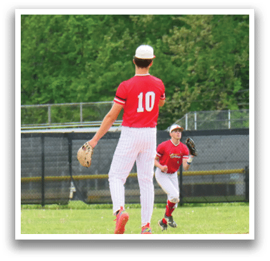 A baseball player wearing a red shirt and white pants is running on the field. Description generated by AI