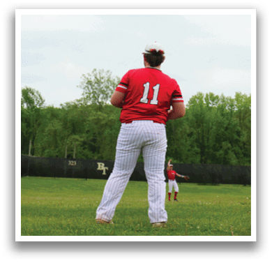 A baseball player wearing a red shirt and white pants stands on a field. Description generated by AI