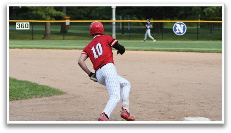 A baseball player wearing a red shirt and white pants running to a base. Description generated by AI