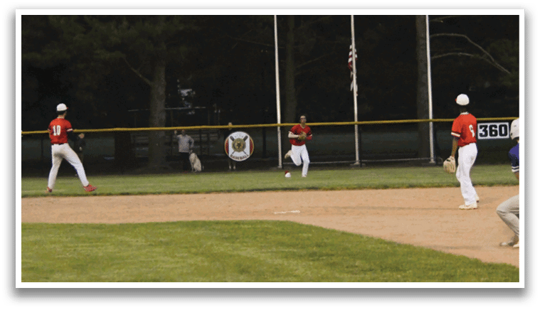 A baseball game is taking place on a field with a man in a purple shirt and white pants holding a bat. Description generated by AI