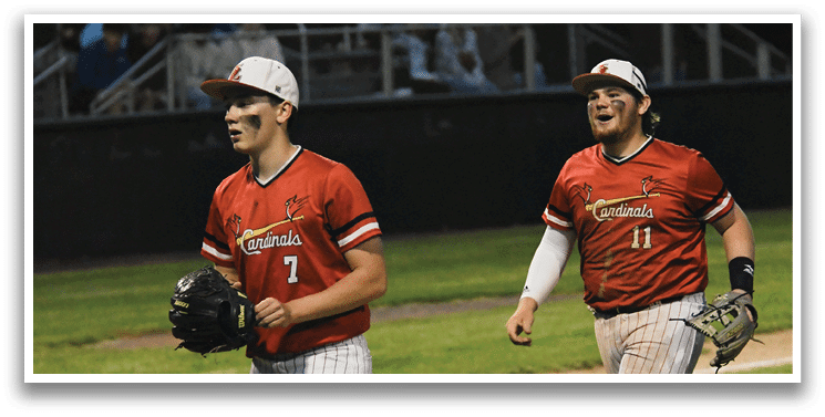 Two baseball players wearing red shirts and white pants. Description generated by AI