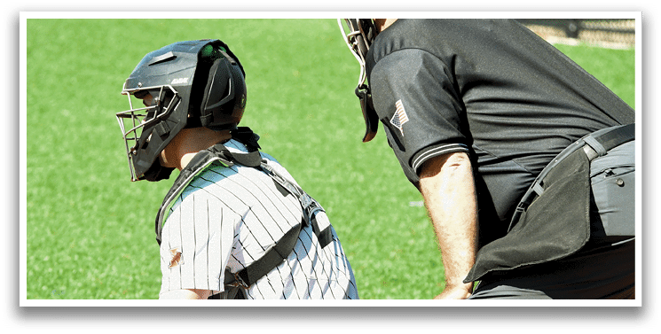 A baseball catcher wearing a helmet and kneeling down. Description generated by AI