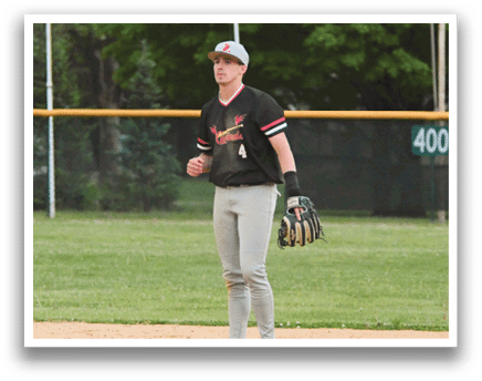 A baseball player wearing a black shirt and grey pants stands on a baseball field. Description generated by AI