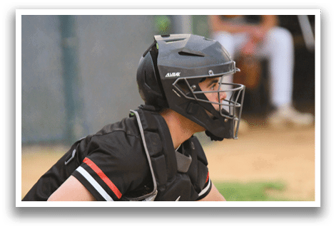 A baseball player wearing a black helmet and chest protector. Description generated by AI