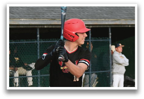 A baseball player in a black shirt and red helmet is holding a bat and getting ready to swing. Description generated by AI