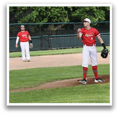 A baseball player wearing a red shirt and white pants is standing on the field. Description generated by AI