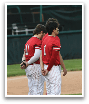 Two baseball players wearing red shirts and white pants. Description generated by AI