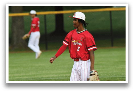 A baseball player wearing a red shirt and white pants. Description generated by AI