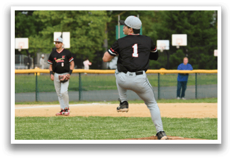 A baseball player in a black shirt and grey pants is pitching a ball. Description generated by AI