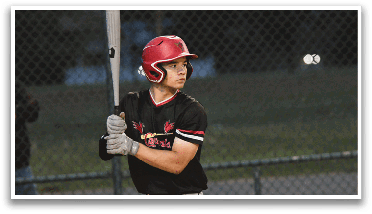 A baseball player in a black and red shirt and white pants holding a bat. Description generated by AI