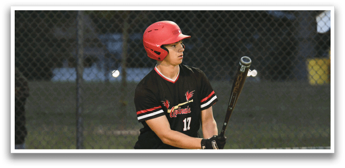 A baseball player in a black and red shirt holding a bat. Description generated by AI
