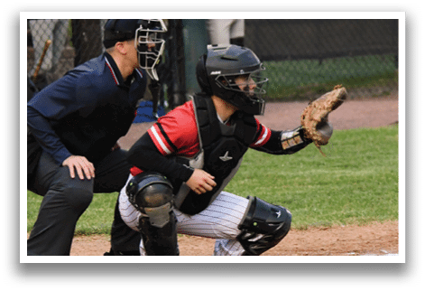 A baseball catcher wearing a black helmet and red shirt. Description generated by AI