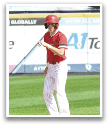 A boy in a red shirt and white pants is standing on a baseball field. Description generated by AI