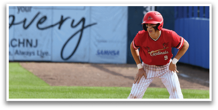 A baseball player in a red shirt and white pants is crouching on the field. Description generated by AI