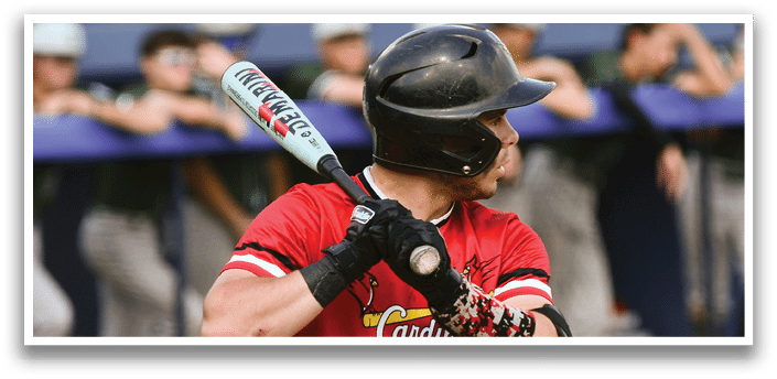 A baseball player in a red and white shirt holding a bat. Description generated by AI