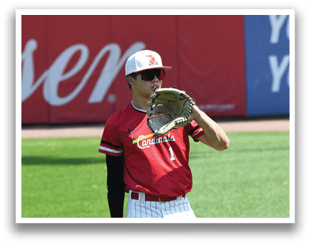 A baseball player wearing a red shirt and white pants. Description generated by AI