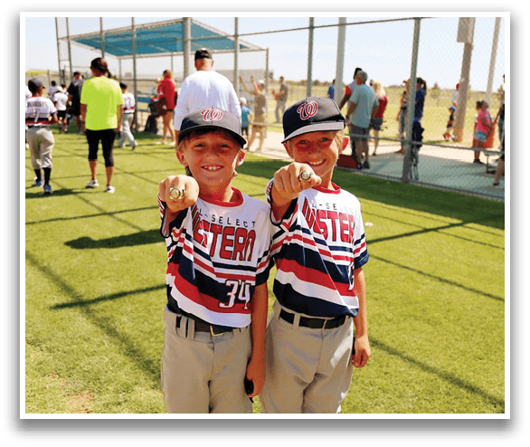 Two young boys wearing baseball uniforms are holding up their gold medals. AI generated content