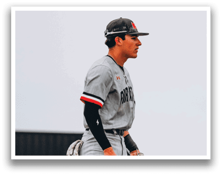 A baseball player wearing a grey uniform and a black hat stands on a field. AI generated content