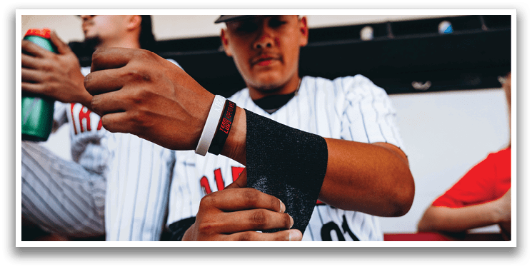 A baseball player is sitting on a bench, holding a black strap in his hand. AI generated content