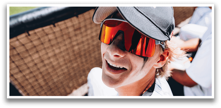 A man wearing a baseball cap and sunglasses is smiling. AI generated content