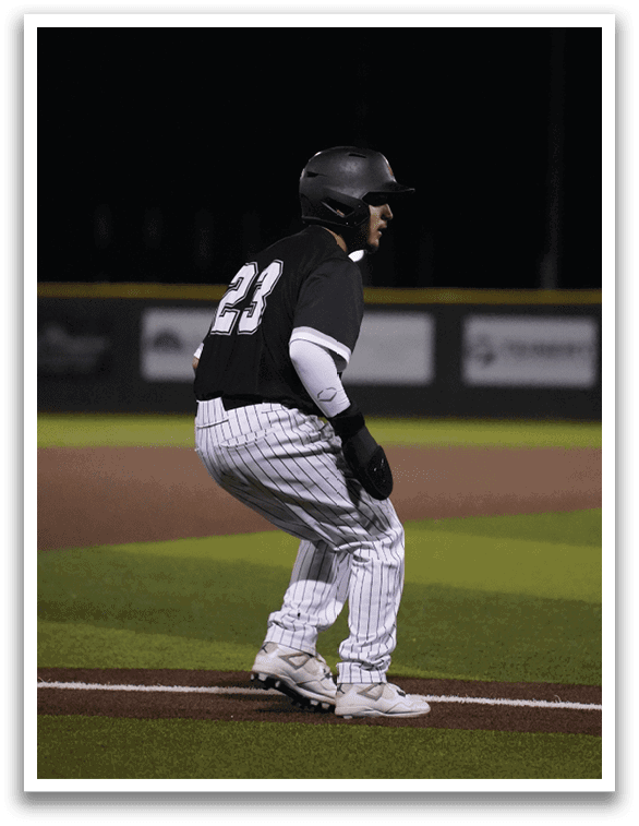 A baseball player is crouching on the field, wearing a black and white uniform. AI generated content