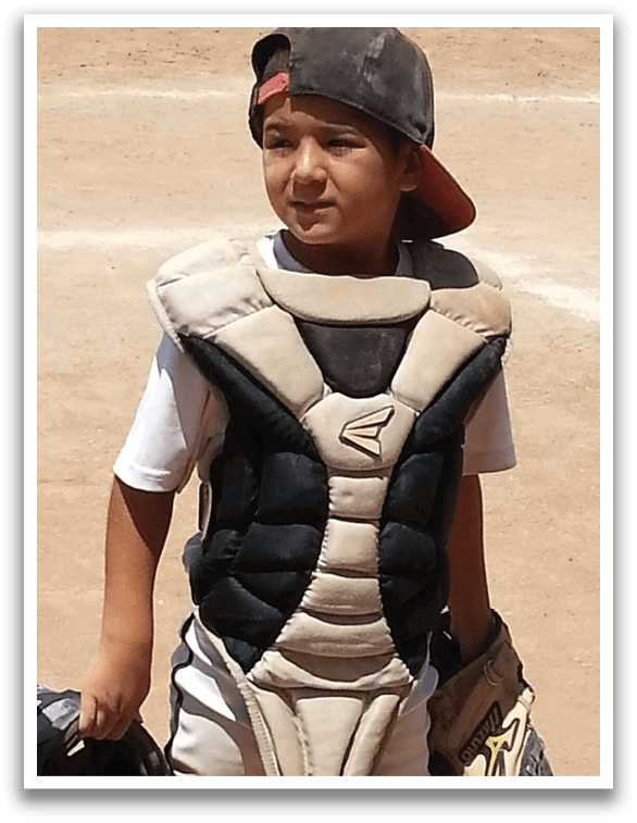 A young boy wearing a catcher's mitt and chest protector. AI generated content
