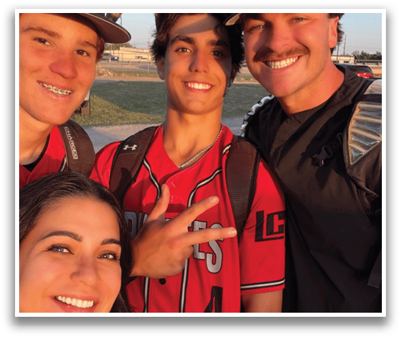 A group of people, including a boy and a girl, pose for a photo. The boy is wearing a baseball uniform and holding a bat. AI generated content
