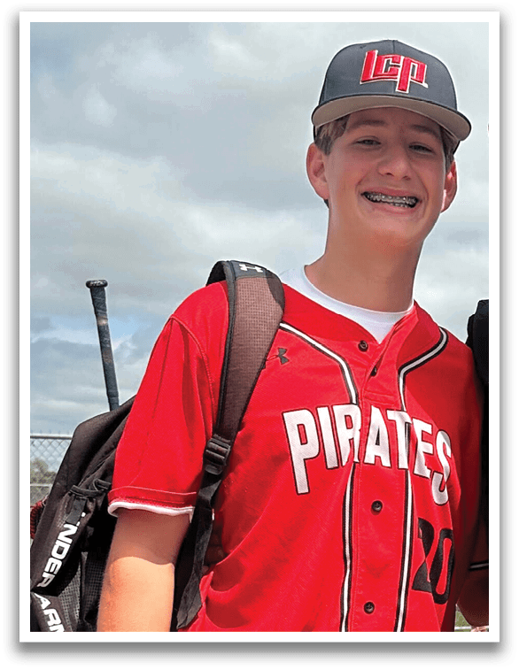 A young man wearing a red shirt and grey pants is holding a baseball bat. AI generated content