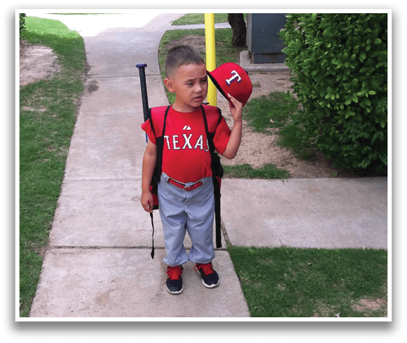 A young boy wearing a red shirt and grey pants holding a yellow bat. Description generated by AI