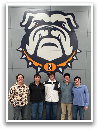 Five young men pose for a picture in front of a large bull dog mascot. Contenido generado con IA