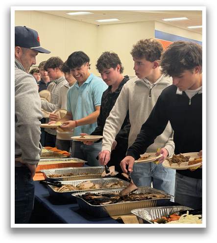 A group of people are gathered around a table filled with food. They are serving themselves from the table, which has a variety of dishes. The people are standing and sitting around the table, enjoying the meal together. Contenido generado con IA