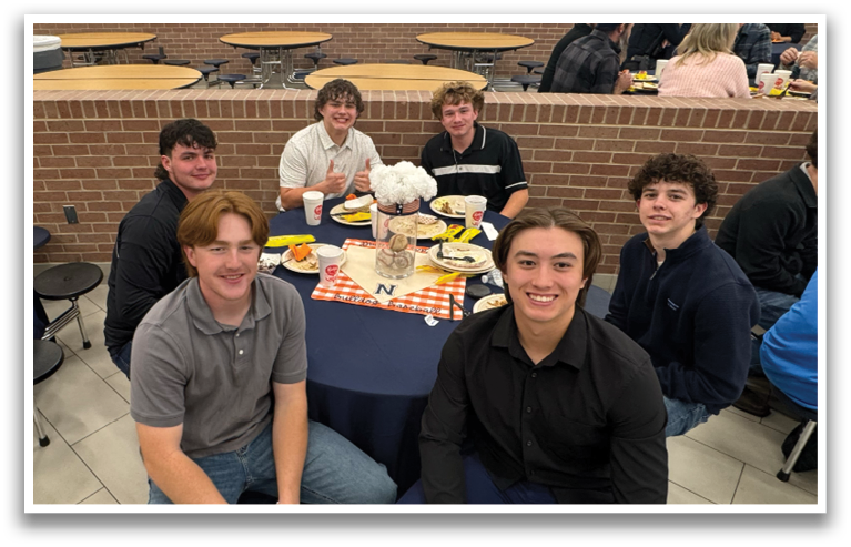 A group of young men are sitting around a dining table, posing for a picture. Contenido generado con IA