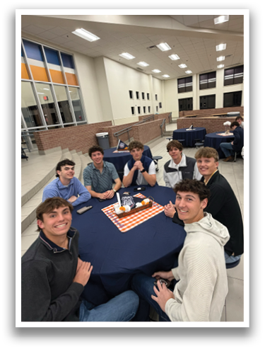 A group of young men are sitting around a table in a room, smiling and posing for a picture. Contenido generado con IA
