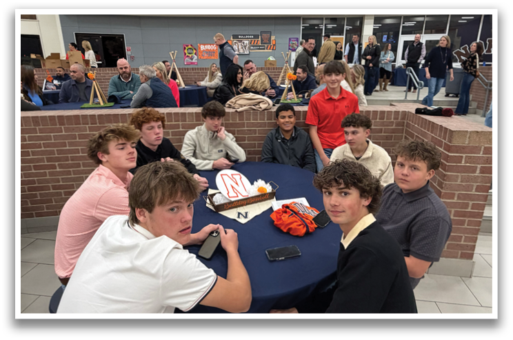 A group of teenage boys are sitting around a table in a room, engaged in conversation. Contenido generado con IA