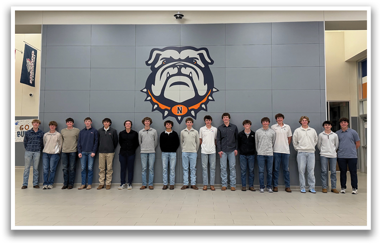 A group of young men are standing in a line in front of a wall with a bulldog mascot. Contenido generado con IA