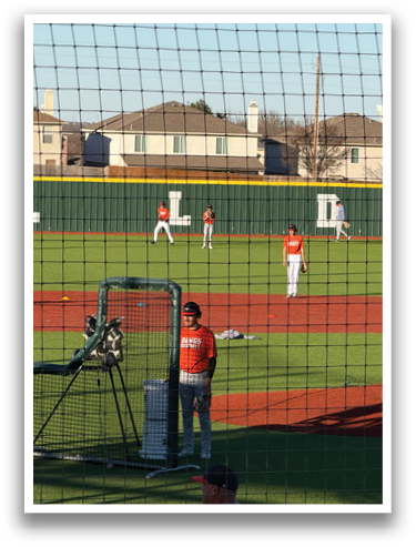 A baseball game is taking place with a group of men playing. One man is holding a baseball bat, ready to swing. The field is surrounded by a fence. Contenido generado con IA
