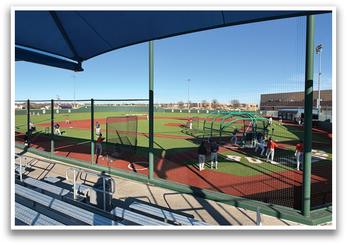 Baseball players are practicing on a field under a blue canopy. Contenido generado con IA