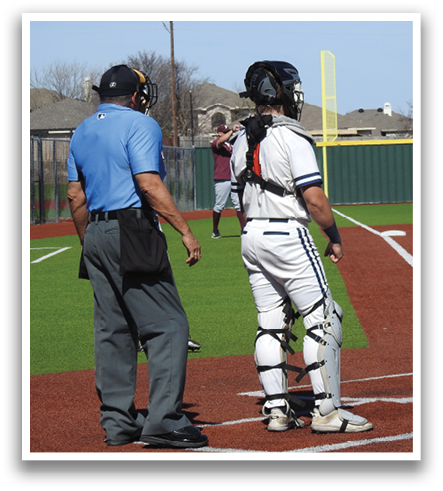 A baseball player is standing on home plate, wearing a helmet and holding a bat. A baseball umpire is also present, standing behind the player. Contenido generado con IA