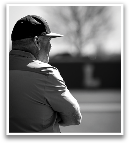 A man wearing a black hat and a white shirt is standing on a baseball field. Contenido generado con IA