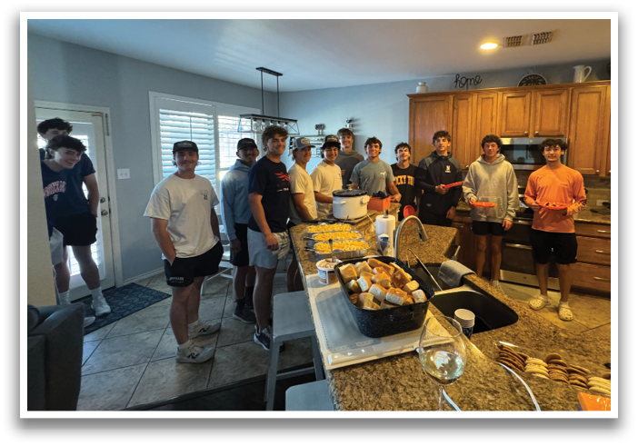 A group of people are standing in a kitchen, posing for a picture. The kitchen is well-equipped with a refrigerator, oven, microwave, and sink. There are also several bowls, cups, and bottles on the countertops. Contenido generado con IA