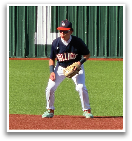 A baseball player in a blue shirt and white pants is standing on a baseball field. Contenido generado con IA