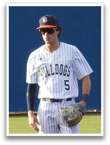 A baseball player stands on the field, wearing a white uniform and a blue hat. Contenido generado con IA