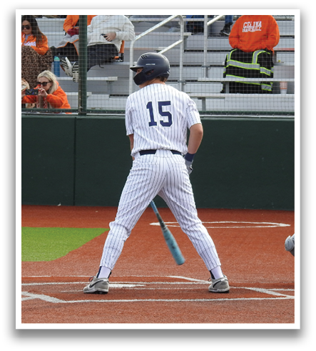 A baseball player wearing a blue helmet and white uniform is standing on a baseball field. Contenido generado con IA