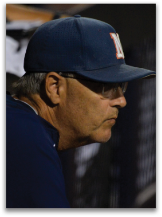 A baseball coach wearing a blue hat and glasses sits on the bench. Contenido generado con IA