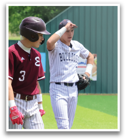 Two baseball players are standing on a field, one of them pointing. A man in a blue shirt is walking by. Contenido generado con IA