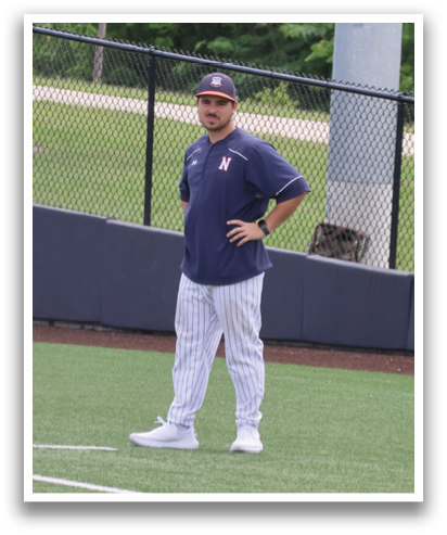 A baseball player stands on the field, wearing a blue shirt and white pants. Contenido generado con IA