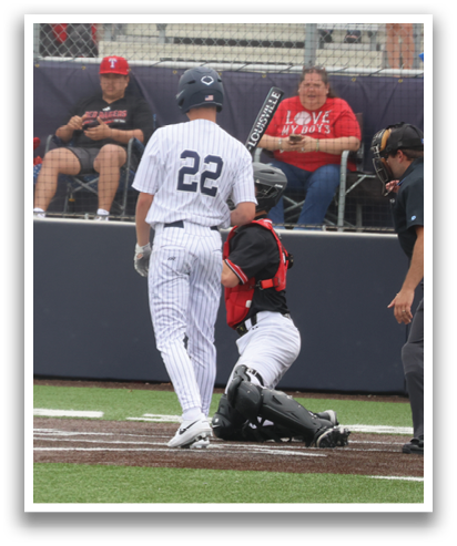 A baseball game is in progress with a player sliding into home plate. The umpire and catcher are also present, with the umpire making a call. The crowd is watching the action, and some are holding umbrellas. Contenido generado con IA