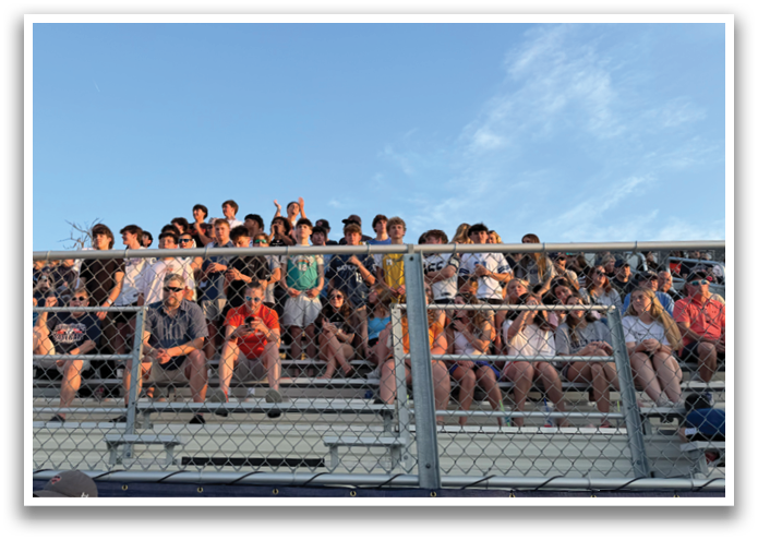 A large group of people are sitting on a bleacher, watching an event. Contenido generado con IA